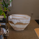 Side view of the illuminated White Ice Onyx coffee table with angular facets and golden veins around its body.