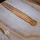 Illuminated onyx tabletop detail showing a winding amber formation surrounded by fine cream and white mineral bands.