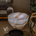 Side view of the illuminated White Ice Onyx coffee table with angular facets and golden veins around its body.