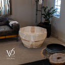 Unlit White Ice Onyx coffee table in a living room, showing its faceted shape and soft ivory and beige coloring.