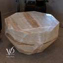 Angled unlit view of the octagonal onyx coffee table with a glossy top, caramel veining, and tapered stone base.