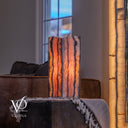 Illuminated Rosa Onyx live-edge table lamp glowing with rose, coral, cream, amber, and charcoal stone banding