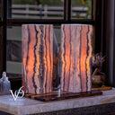 Handcrafted Rosa Onyx bedside lamp pair glowing beside a vintage window in a luxury interior