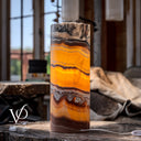 Illuminated Miami Sunset Onyx cylinder lamp glowing with golden orange, amber, red, and dark brown banding