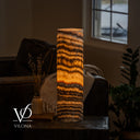 Illuminated Tangerine Onyx cylinder table lamp with a broad golden center and wavy charcoal bands.