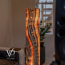 Tangerine Onyx floor lamp glowing beside a window, with wavy orange, cream, and charcoal vertical bands.