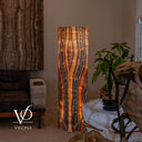 Illuminated Tangerine Onyx floor lamp beside a leather chair, with a pale amber center and dark vertical stone bands.