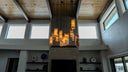 Modern wooden hanging light fixture with multiple cylindrical shades in warm tones.