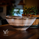 Decorative bowl with agate-like pattern on a wooden surface, blurred plant in the background