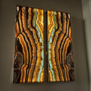 Two-panel agate wall art with vibrant orange, brown, and teal stripes against a dark background.