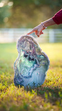 White marble heart-shaped decorative stone with green and blue accents, placed on grass.
